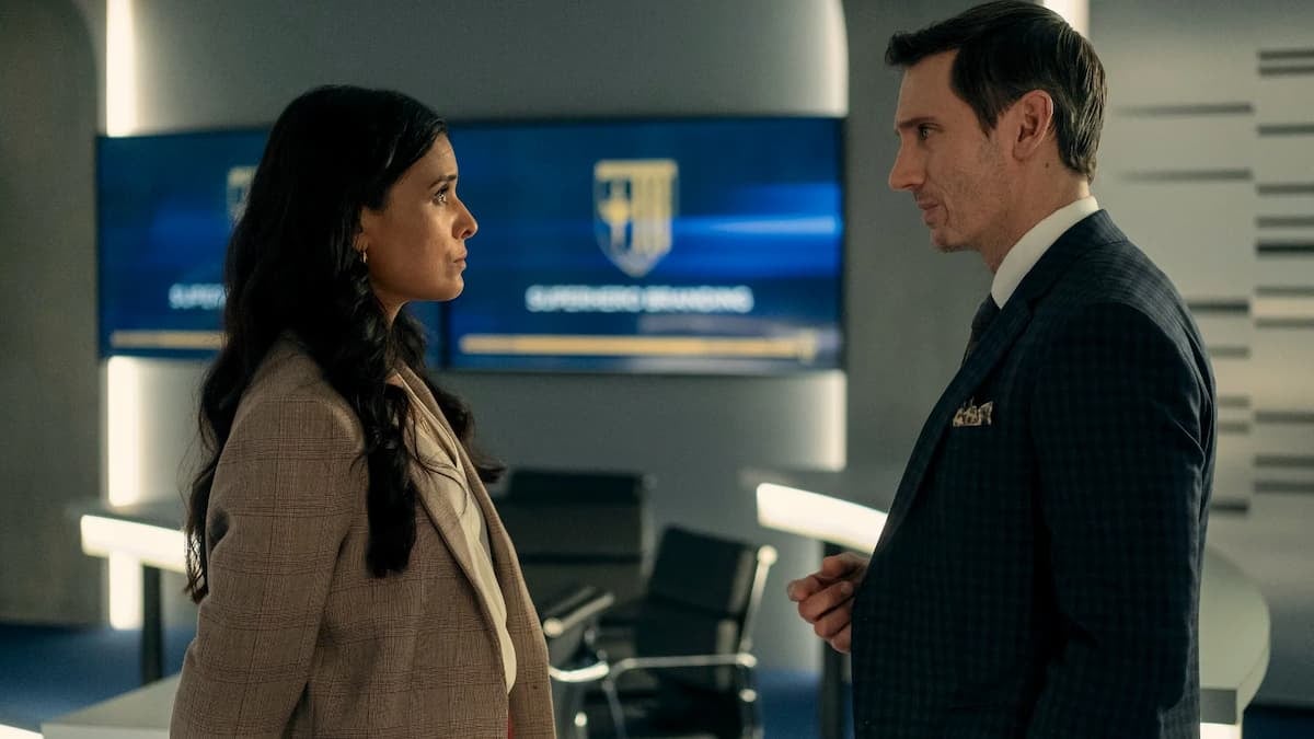 A woman in a brown jacket facing a man in a black jacket. Indira Shetty and Tek Knight in Gen V Season 1.