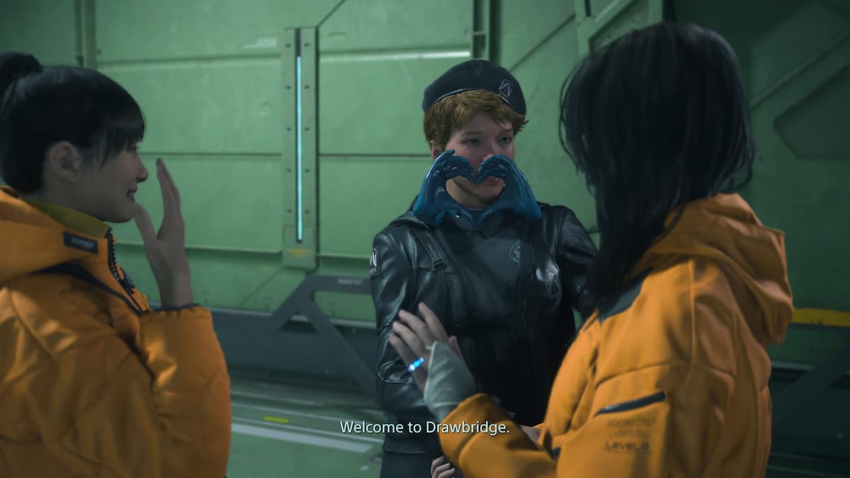 Three women in Death Stranding 2. Two of them are in yellow jackets, one is in a black coat making a heart symbol with her hands.