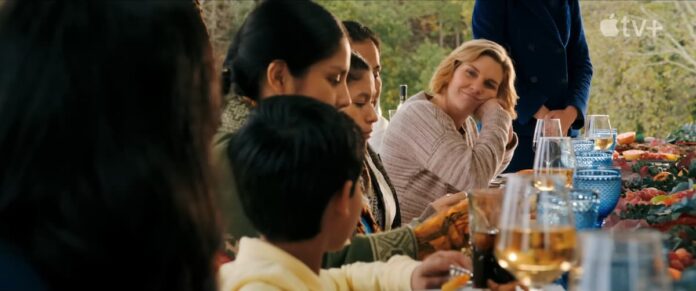pluribus screenshot A blonde woman sitting at a table and smiling in Pluribus.