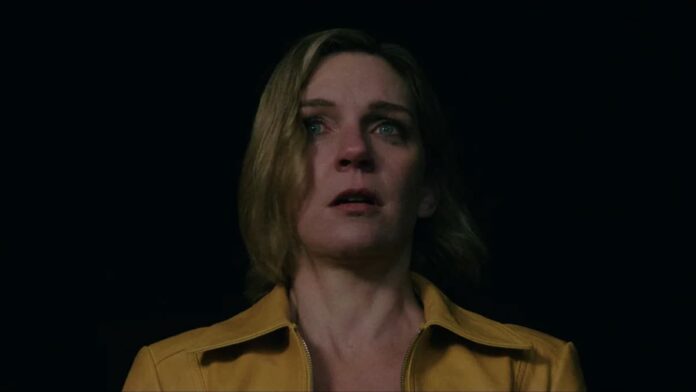 pluribus carol A woman in a yellow jacket against a dark background in Pluribus.