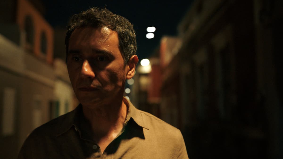 A man standing in a darkened street in Pluribus.