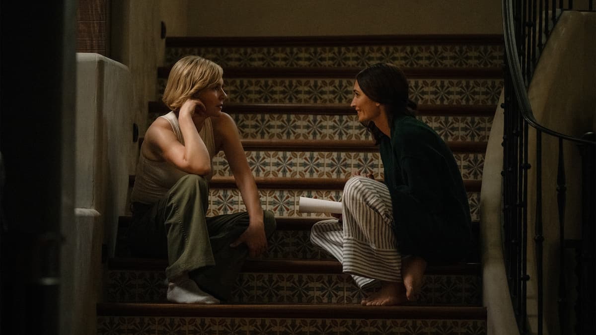 Two women sitting on the stairs in Pluribus.