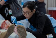Joy Kwon Is Quickly Becoming My Favorite New Character in The Pitt A lady with glasses operating on a patient.