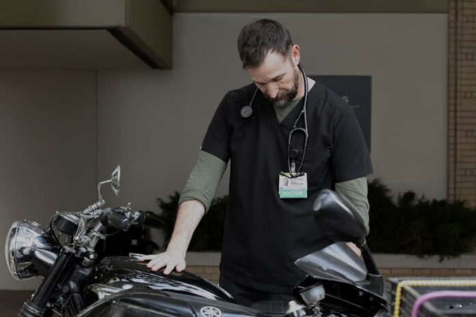 pitt noah wyle A man touching a motorcycle in The Pitt Season 2.